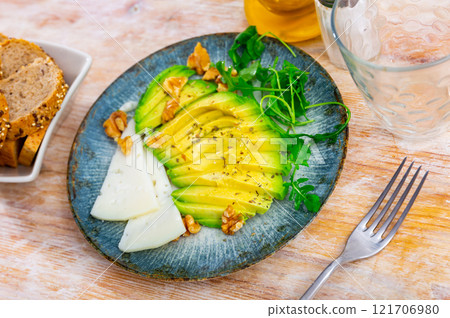Avocado and cheese served with arugula and walnuts Avocado and cheese served with arugula and walnuts 121706980