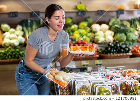 Young woman shopper chooses papaya and roots in shop Young woman shopper chooses papaya and roots in shop 121706981