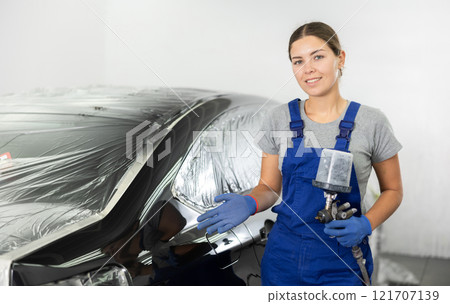 Female car painter preparing for work in auto shop Female car painter preparing for work in auto shop 121707139