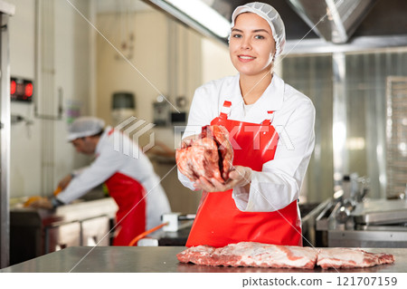 Female seller demonstrating meat in butcher shop 121707159
