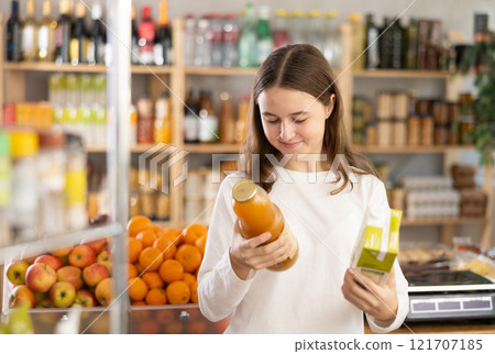 Teenage girl choosing peach and apple juices Teenage girl choosing peach and apple juices 121707185