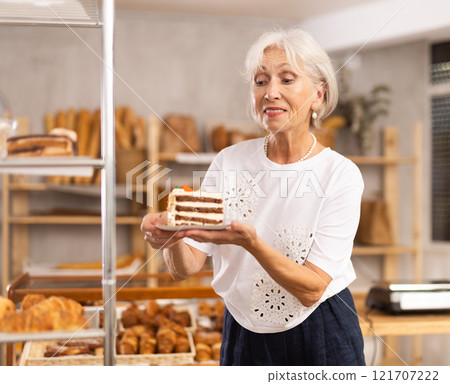 Elderly woman with piece of cake in bakery Elderly woman with piece of cake in bakery 121707222