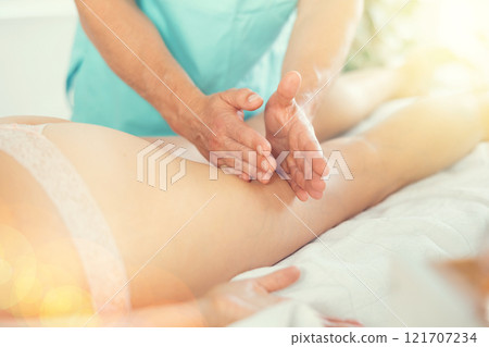 The masseur makes a massage on the legs 121707234