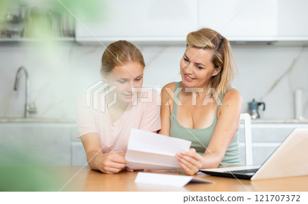 Joyful and overjoyed mother and teenager daughter reads letter and learn good news Joyful and overjoyed mother and teenager daughter reads letter and learn good news 121707372