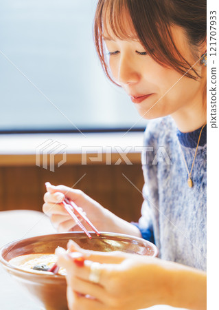 Happy young woman eating delicious ramen 121707933