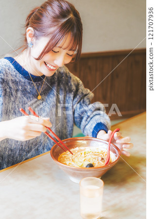 Happy young woman eating delicious ramen 121707936