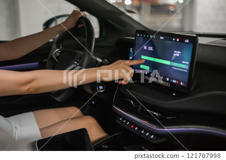 Close up woman checking battery charge on a monitor in an electric car. Close up woman checking battery charge on a monitor in an electric car. 121707998