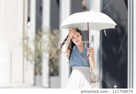 A hot-looking businesswoman walking with a parasol in an office district A hot-looking businesswoman walking with a parasol in an office district 121708679