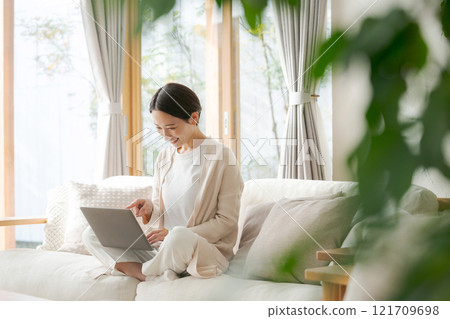 Woman working on a computer on the sofa Woman working on a computer on the sofa 121709698
