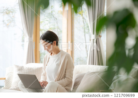 Woman working on a computer on the sofa 121709699