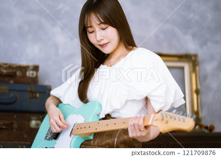 拿著電吉他的長髮年輕女子 121709876