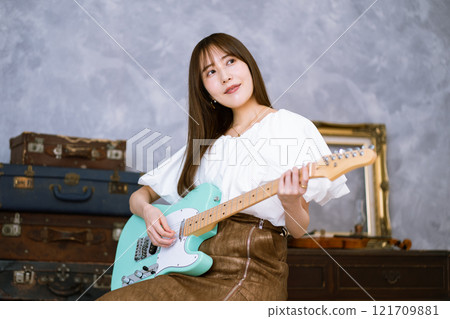 拿著電吉他的長髮年輕女子 121709881