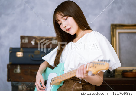 Long-haired young woman with an electric guitar 121709883