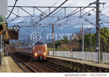 A conventional express train bound for Izumo, 273 series Yakumo No. 7, running on the Sanin Main Line with tourists on board for the New Year's holiday, with the snow-capped Mt. Daisen in the background 121710216