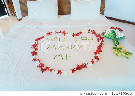 message WILL YOU MARRY ME made of flower petals with bouquet and Heart shape on bed. Idea for marriage proposal, romantic surprise, wedding and engagement concept 121710500