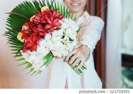 Woman hand wearing a diamond ring and holding flower bouquet. Idea for marriage proposal, romantic surprise, wedding, engagement and valentines day concept 121710501