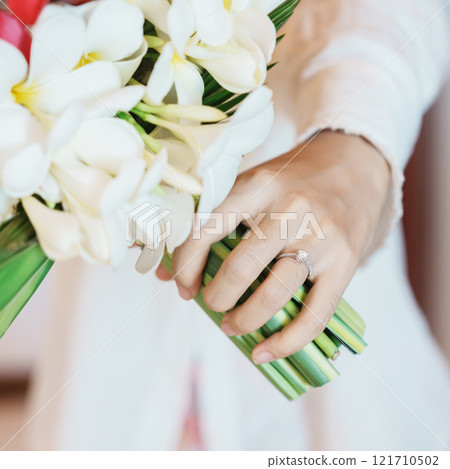 Woman hand wearing a diamond ring and holding flower bouquet. Idea for marriage proposal, romantic surprise, wedding, engagement and valentines day concept 121710502