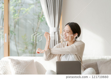 一位女士在電腦上工作並伸展身體 一位女士在電腦上工作並伸展身體 121710660