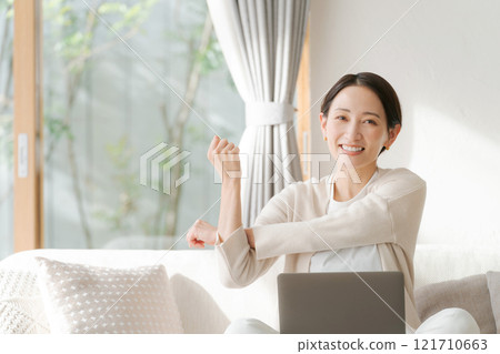 一位女士在電腦上工作並伸展身體 一位女士在電腦上工作並伸展身體 121710663