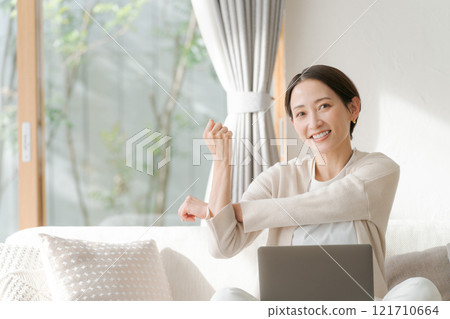 一位女士在電腦上工作並伸展身體 一位女士在電腦上工作並伸展身體 121710664