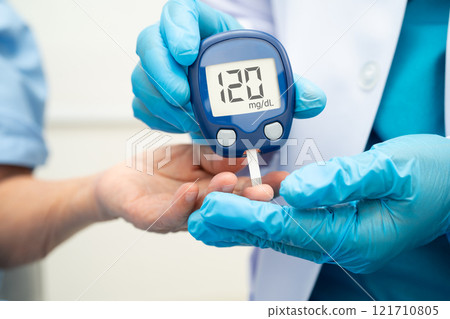 Asian doctor using digital glucose meter for check sample blood sugar level to treatment diabetes. Asian doctor using digital glucose meter for check sample blood sugar level to treatment diabetes. 121710805