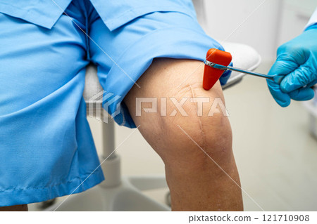 Asian doctor knock on knee reflex nerve for check and treatment senior patient in hospital. 121710908