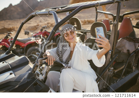 Woman tourist on ATV and ATV safari with desert background of Sharm el-Sheikh, Egypt taking selfie with background 121711614