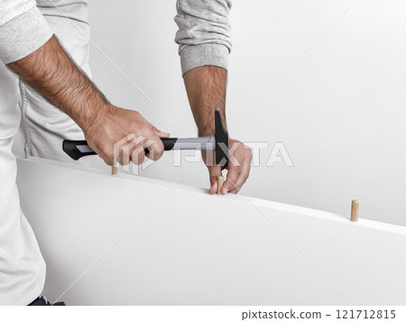 Male assembling furniture with hammer and wood dowels Male assembling furniture with hammer and wood dowels 121712815