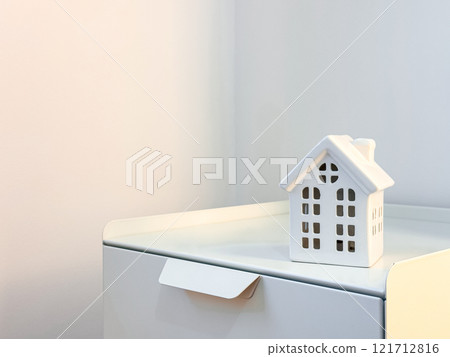 Minimalist white ceramic house on modern nightstand in bright interior space Minimalist white ceramic house on modern nightstand in bright interior space 121712816