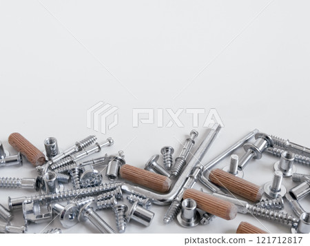 Assorted metal screws and wooden dowels on a white surface 121712817