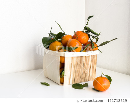 Fresh oranges in wooden basket with green leaves on white background 121712819