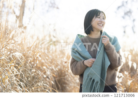 A woman walking through a field of silver grass A woman walking through a field of silver grass 121713006
