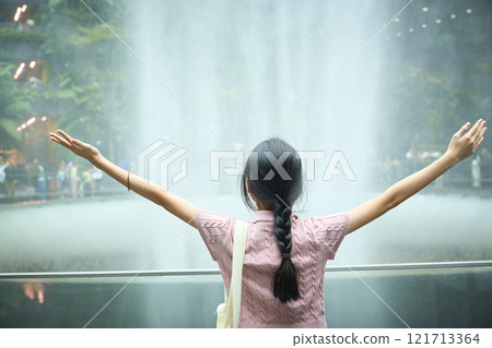 Young tourist girl embracing the beauty of indoor waterfall in singapore jewel changi airport 121713364