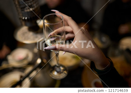 A woman holds a cocktail in her hand, with her fingers wrapped around the glass A woman holds a cocktail in her hand, with her fingers wrapped around the glass 121714639