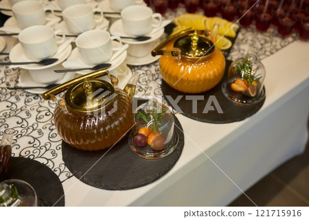 The elegant teapots, cups, and tea are beautifully arranged on a sophisticated table 121715916