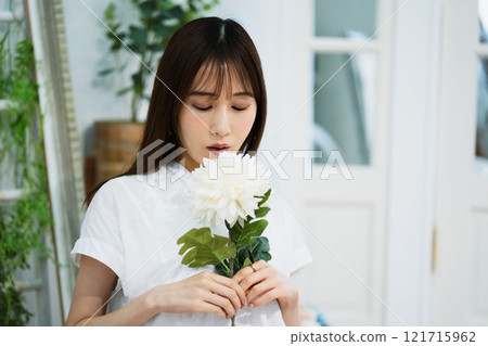 Young woman with long black hair holding white flowers Young woman with long black hair holding white flowers 121715962