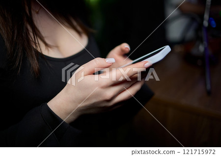 Woman in stylish dress with chic manicure using smartphone in closeup shot Woman in stylish dress with chic manicure using smartphone in closeup shot 121715972