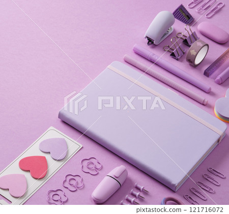 Pastel purple stationery background with notepad, paper clips, writing supplies, post-it notes, stapler. 121716072