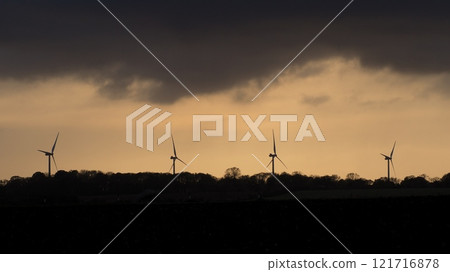 Wind turbines silhouetted against a stormy and overcast evening sky at sunset Wind turbines silhouetted against a stormy and overcast evening sky at sunset 121716878