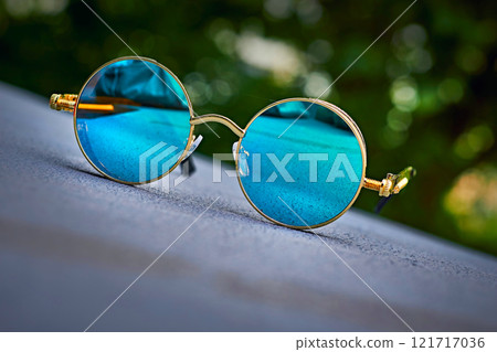 Vintage cool gold sunglasses with blue emerald lenses on asphalt 121717036