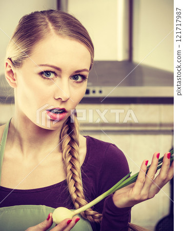 Woman in kitchen holds green fresh chive 121717987