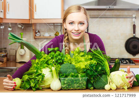 Smiling woman in kitchen with green vegetables Smiling woman in kitchen with green vegetables 121717999