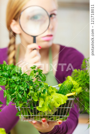 Woman looking magnifier at vegetables Woman looking magnifier at vegetables 121718011