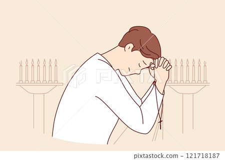 Man prays while standing in church near candlesticks, holds christian crucifix and closes eyes Man prays while standing in church near candlesticks, holds christian crucifix and closes eyes 121718187