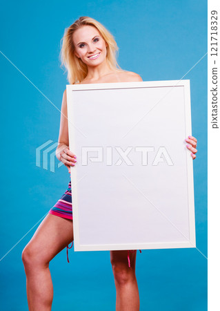 Happy positive blonde woman holding blank white board 121718329