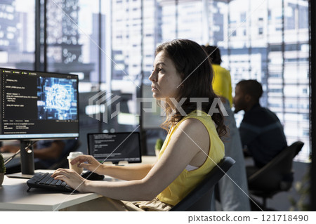 Data scientist utilizing cloud computing resources and platforms to train and deploy large scale machine learning models. Woman in business office monitoring and maintaining company systems 121718490