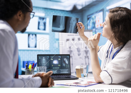 Woman physician reading x ray diagnostics for a patient in medical office, doing a test results scan interpretation to help person with disease. Providing treatment and advice for recovery. 121718496