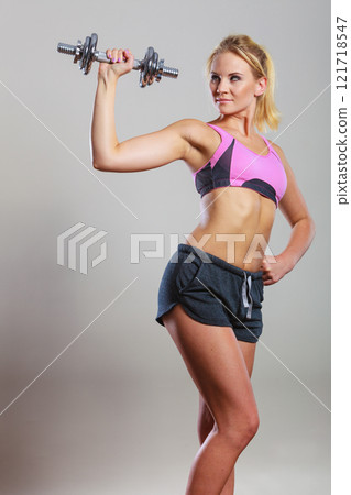 Fit woman lifting dumbbells weights 121718547