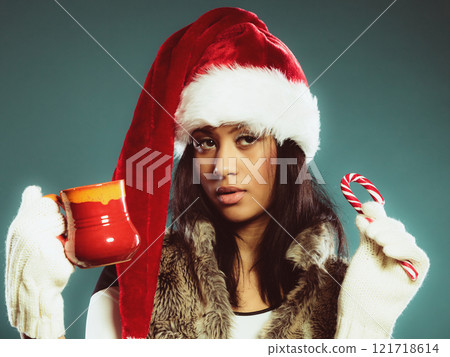 Winter girl santa helper hat holds red mug 121718614