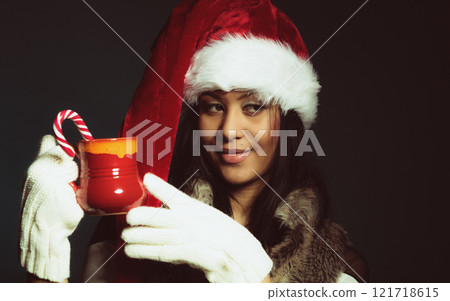 Winter girl santa helper hat holds red mug 121718615